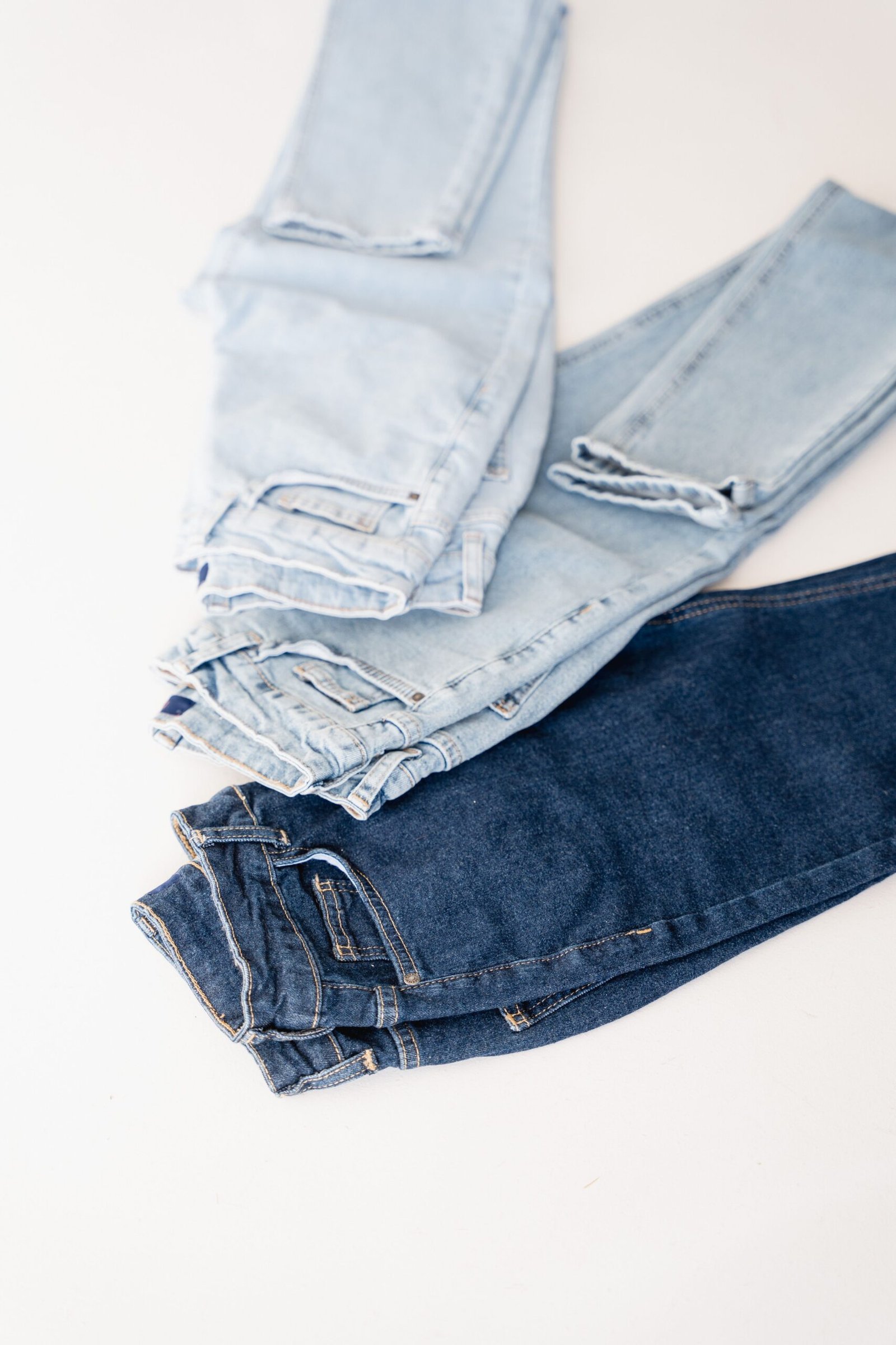 Light and dark blue denim jeans arranged on a white surface.